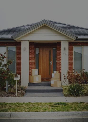 Brick house with a wooden front door and delivery boxes on the steps in Australia